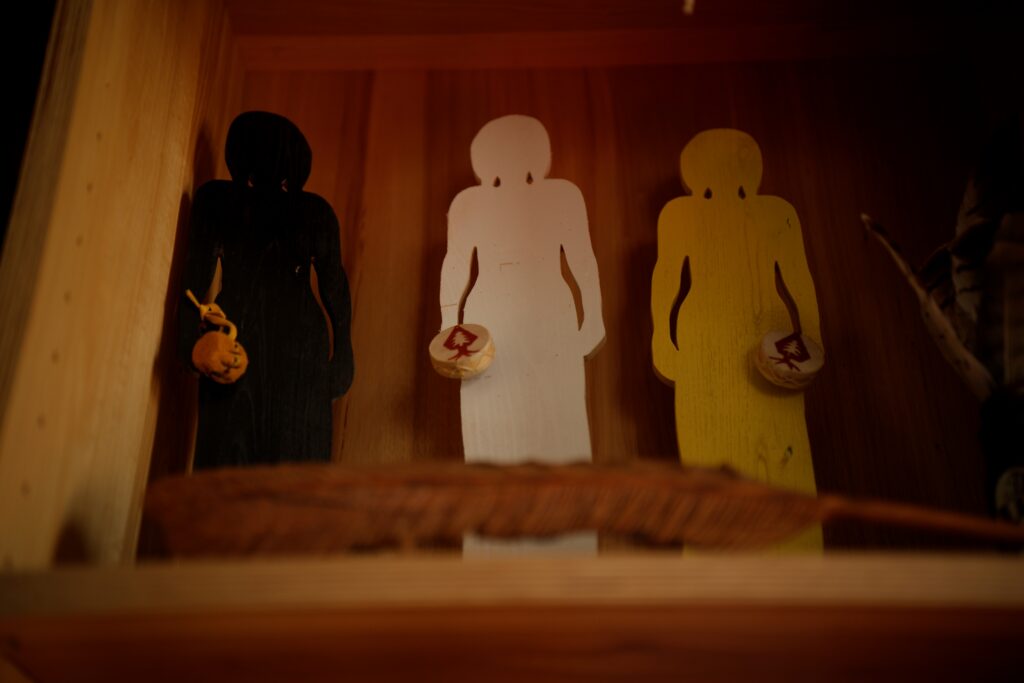 Conni's artwork featuring the outlines of three figures, one color black, another color white, and final woodgrain.