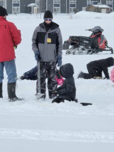 Lucas Roff, Program Manager at Inter-Tribal Council of Michigan assists an Ojibwe Charter School student with ice fishing at Waiska Bay behind Bay Mills Resort and Casino.